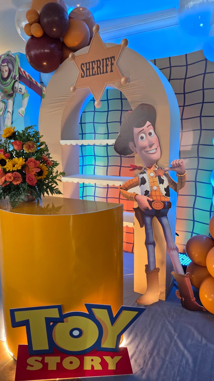 Arco Sheriff de Toy Story con figura de Woody, arreglo de girasoles y barra amarilla