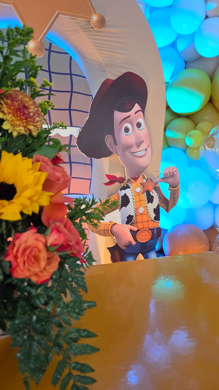 Detalle del arco de Toy Story con figura de Woody y arreglo floral de girasoles y rosas