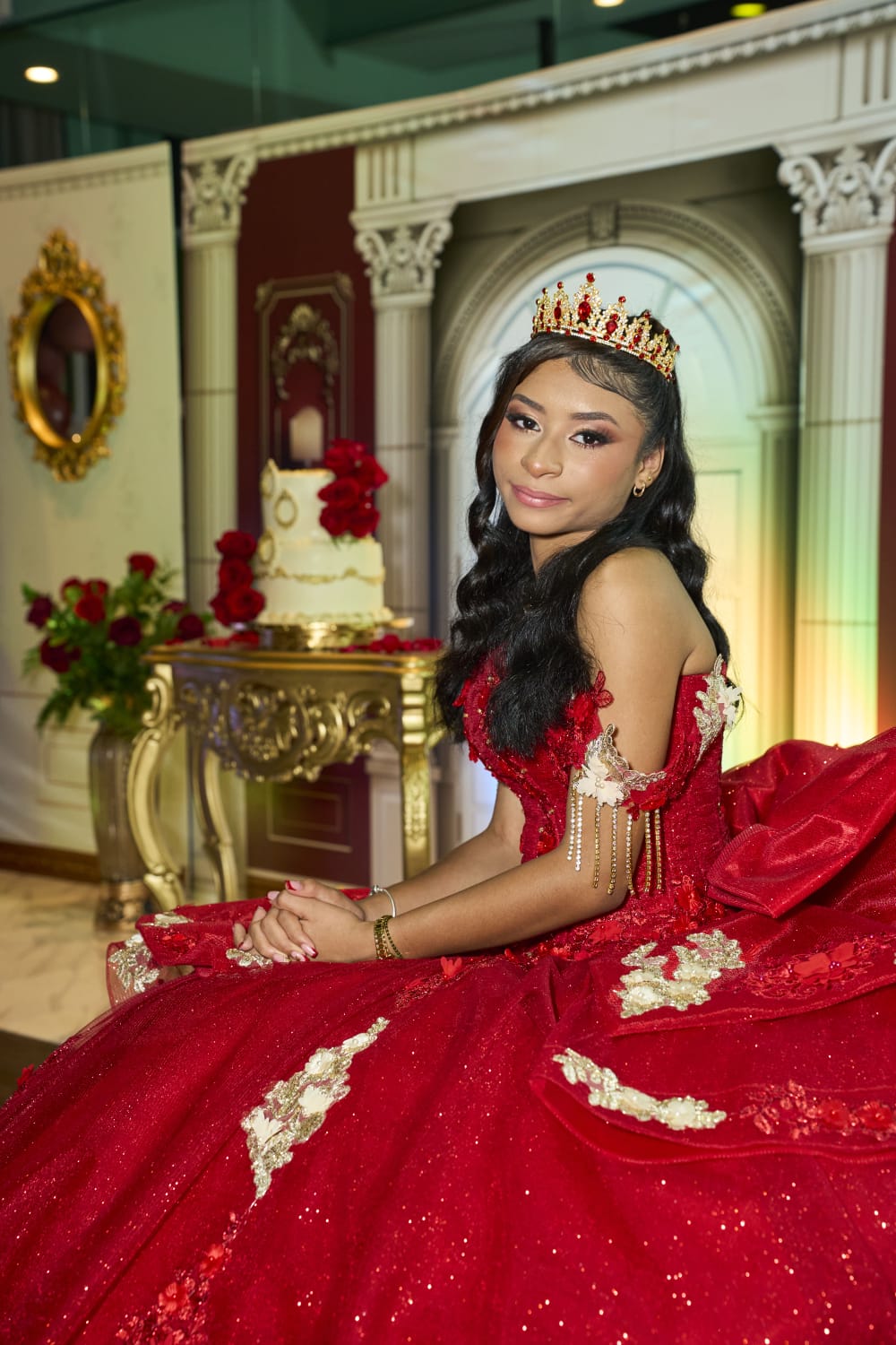 Lía Sofía con vestido rojo y corona frente al backdrop victoriano de sus XV años