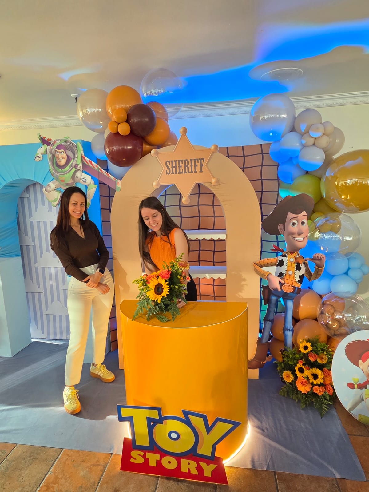Montaje temático de Toy Story con arco de globos y arreglo floral de girasoles, ejemplo de la fusión de globos y flores