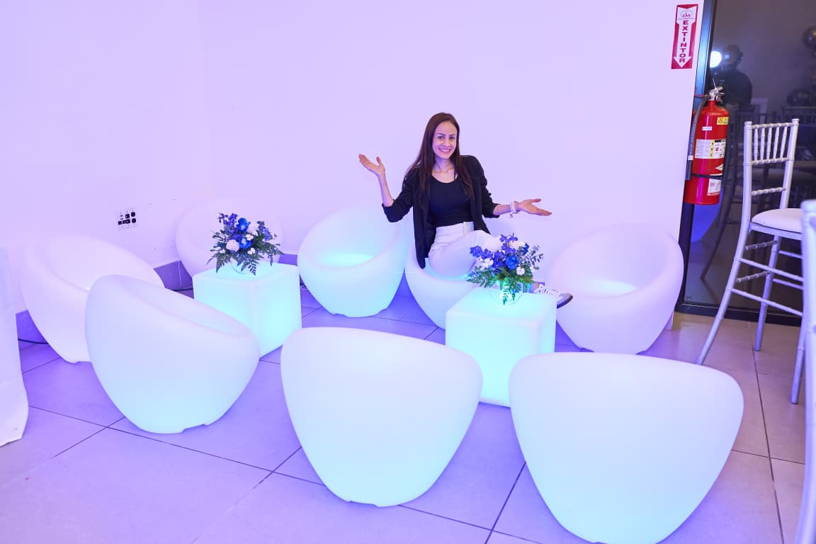 Sofía sentada en el lounge de módulos LED decorado con flores azules para sus XV años