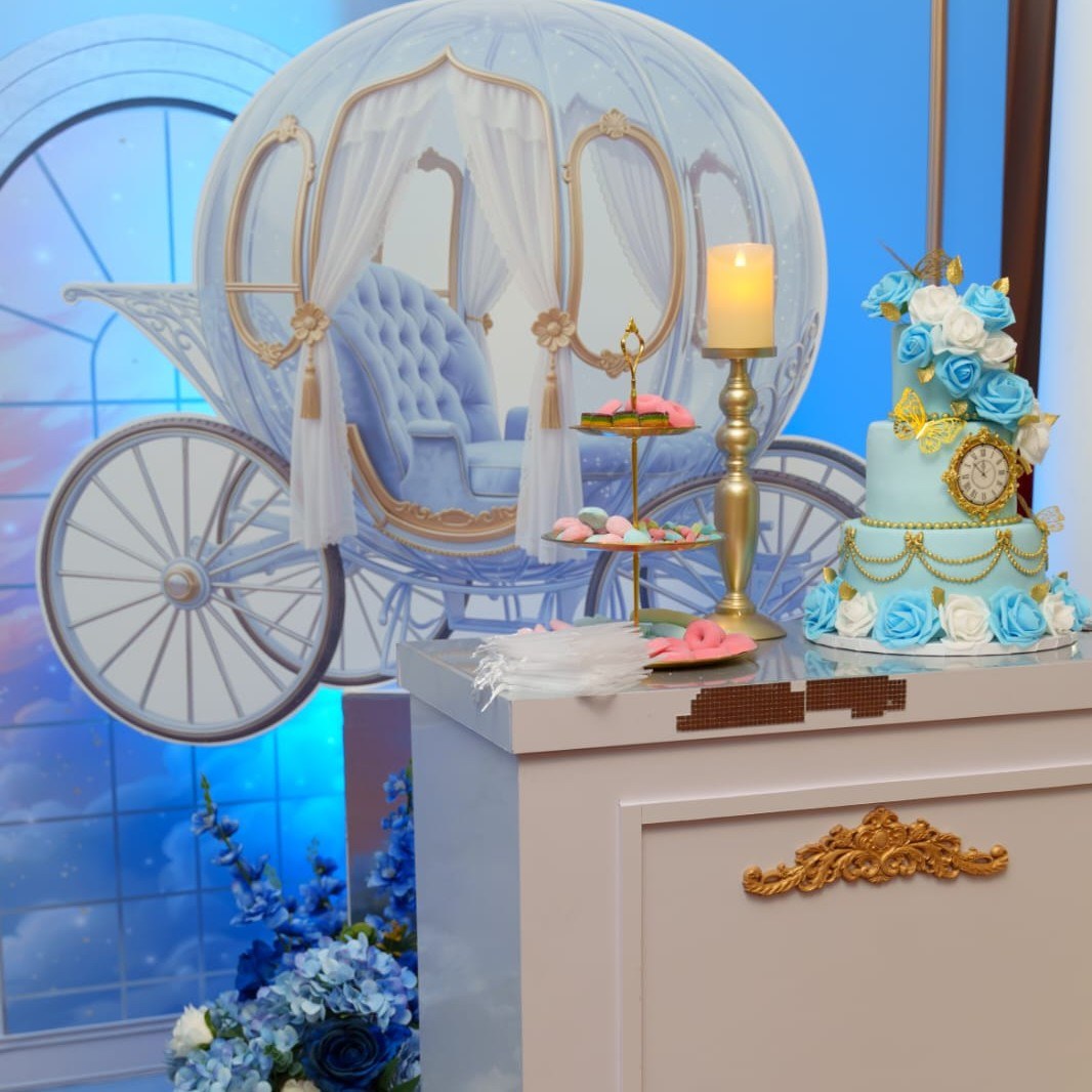 Carruaje de Cinderella de fondo junto a mesa de pastel y arreglo floral para la Experiencia Creativa Medium