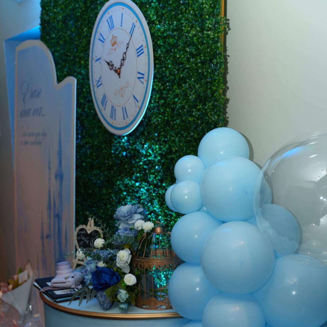 Detalle del reloj decorativo sobre pared de jardín vertical con globos azules para la Experiencia Creativa Medium